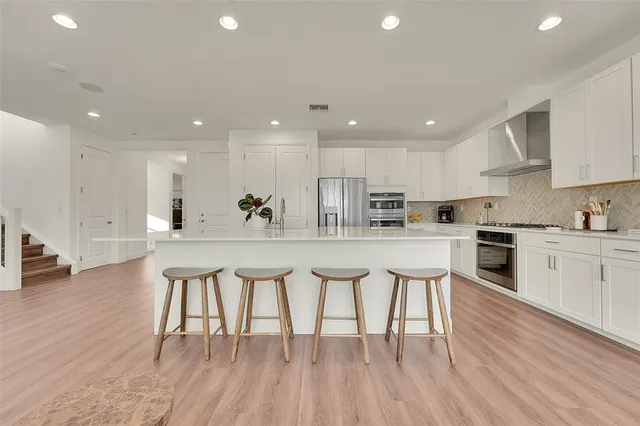 a kitchen with white cabinets stainless steel appliances and dining table