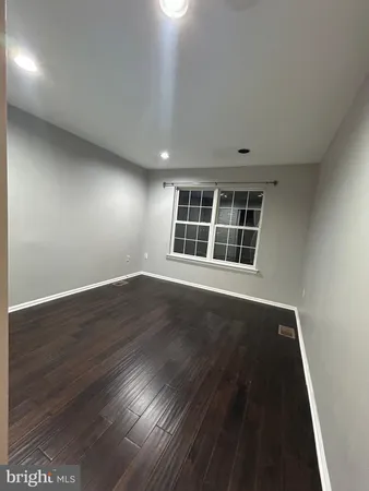 a view of an empty room with wooden floor and windows