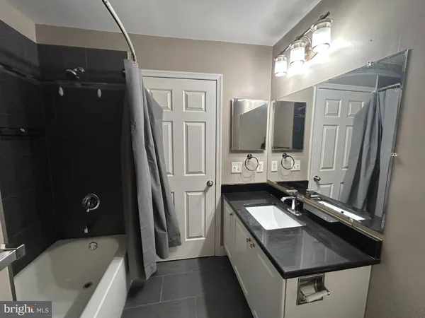 a bathroom with a sink double vanity granite tub shower and mirror