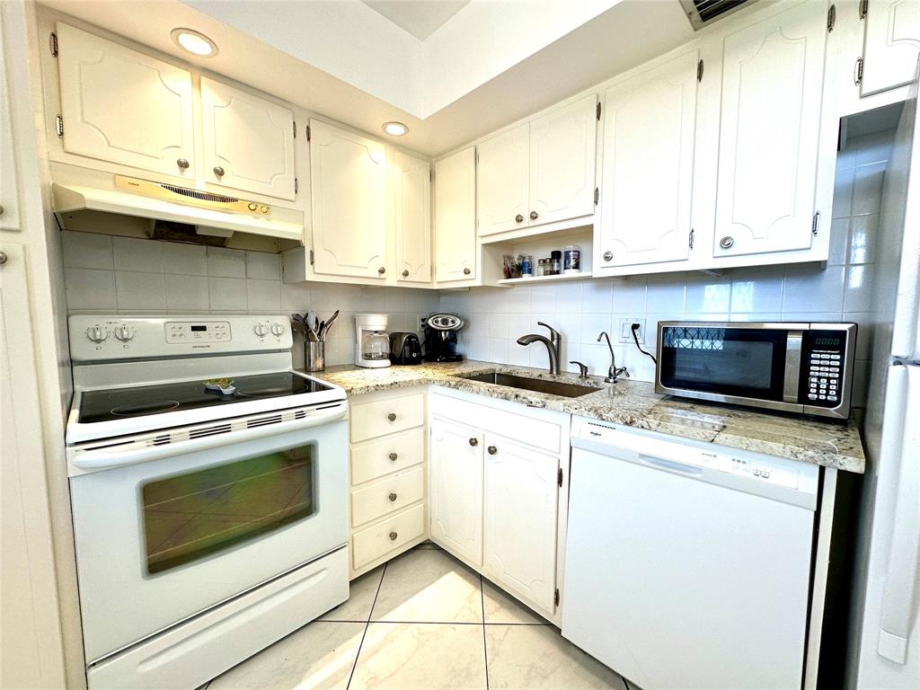 2671 South Course Drive, Unit 802 Pompano Beach, FL 33069 - Photo 2 of 34 a kitchen with stainless steel appliances granite countertop a sink a stove and microwave
