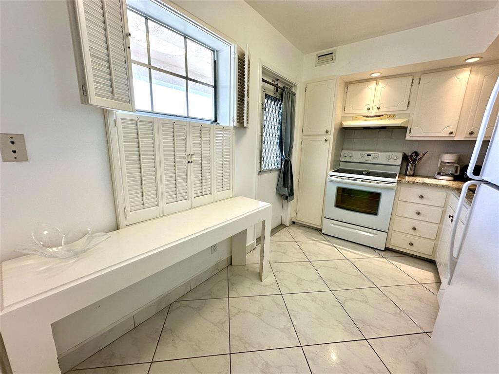 2671 South Course Drive, Unit 802 Pompano Beach, FL 33069 - Photo 6 of 34 a kitchen with granite countertop a stove a sink and a microwave