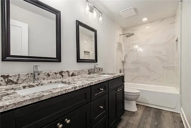 a bathroom with a granite countertop sink toilet a large mirror a bathtub and shower