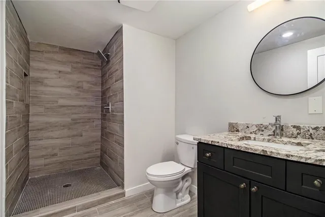 a bathroom with a granite countertop sink toilet a mirror and shower