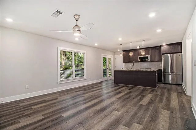 a large kitchen with kitchen island a island wooden floors stainless steel appliances and a window