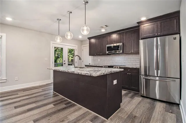 a kitchen with kitchen island granite countertop stainless steel appliances a stove cabinets a refrigerator and a sink