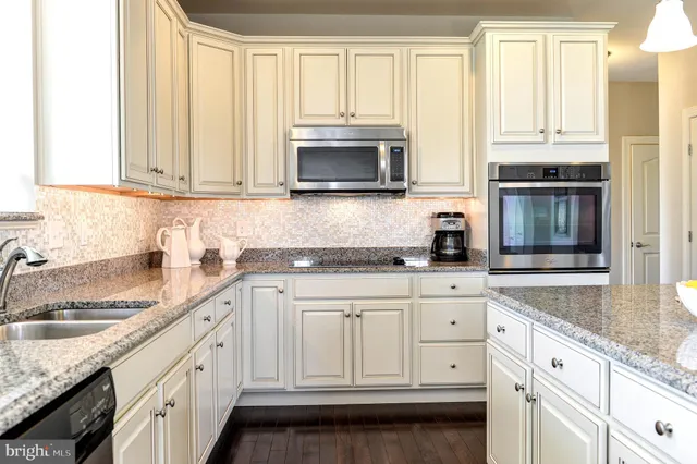 a kitchen with granite countertop white cabinets and stainless steel appliances