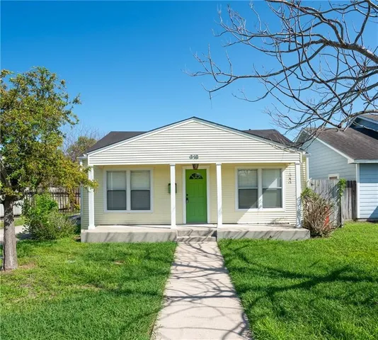 a front view of a house with a yard and potted plants