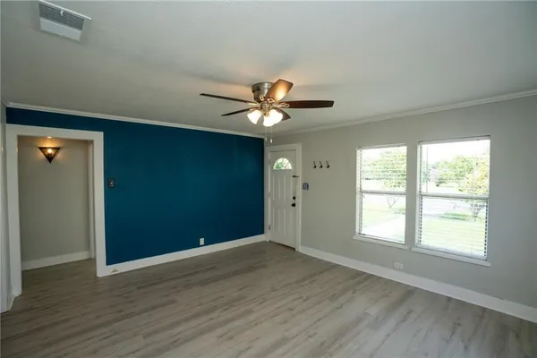a view of an empty room with wooden floor and a window