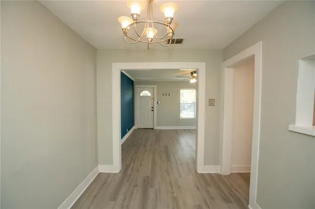 a view of a hallway with wooden floor and chandelier