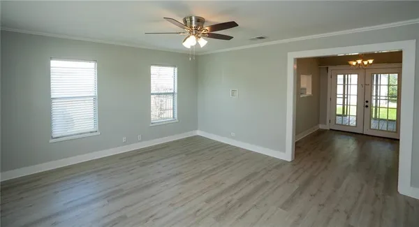 an empty room with wooden floor and windows