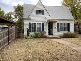 a view of a house with a yard and lawn chairs under an umbrella