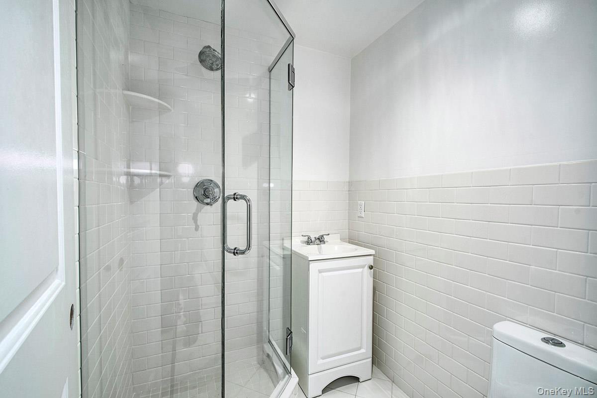 8 Walden Lane Rye, NY 10580 - Photo 18 of 28 Full bath featuring tile wainscoting, stall shower and vanity