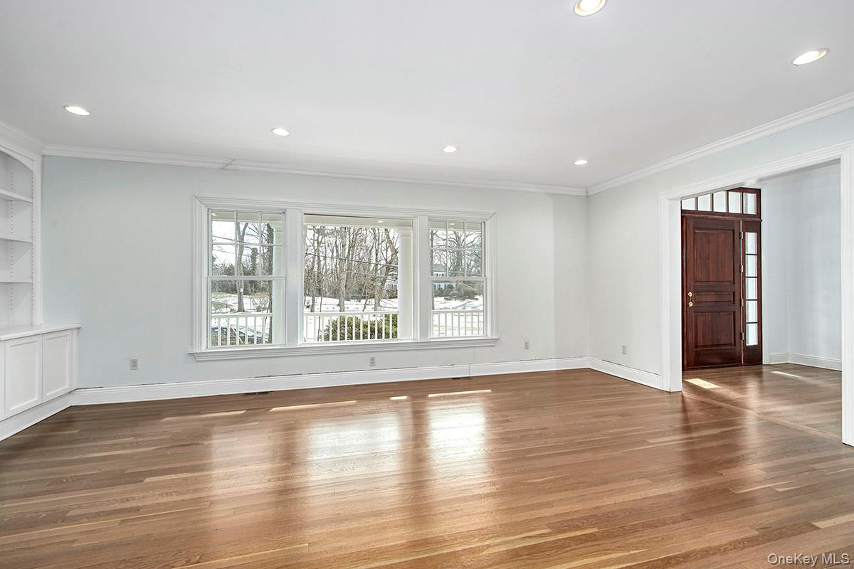 8 Walden Lane Rye, NY 10580 - Photo 2 of 28 Spacious living room with natural sunlight, hardwood floors, intricate moldings, and stone wood burning fireplace