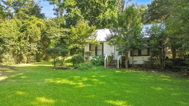 a backyard of a house with plants and large trees