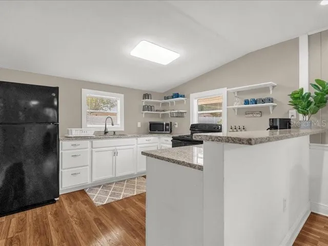 a kitchen with granite countertop a sink stainless steel appliances and cabinets