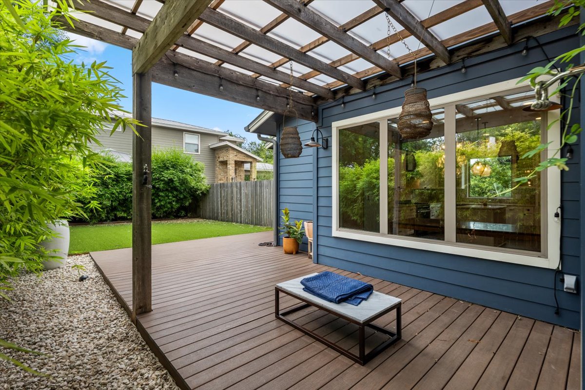 913 Stobaugh Street, Unit B Austin, TX 78757 - Photo 6 of 40 An inviting backyard oasis offers a spacious wooden deck with a charming pergola and a verdant artificial lawn.