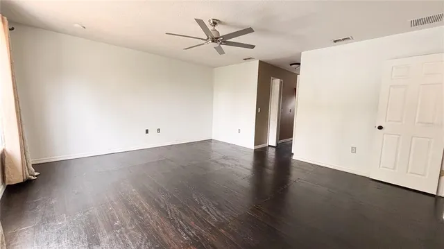 an empty room with wooden floor and a ceiling fan