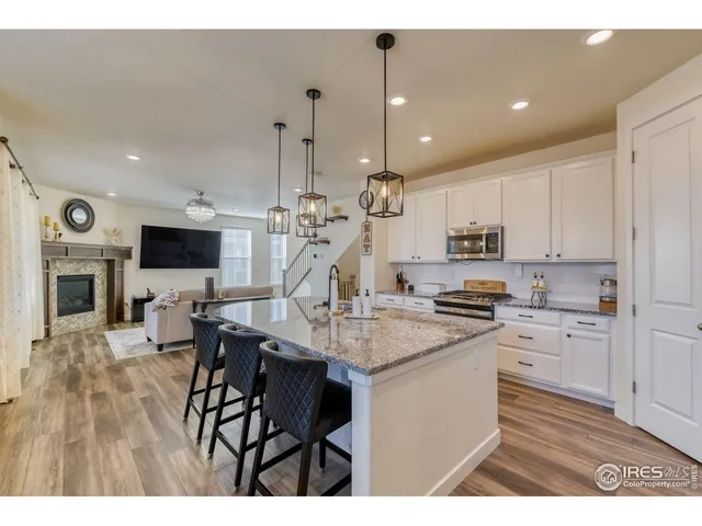 a open kitchen with stainless steel appliances kitchen island granite countertop a stove a sink dishwasher and a microwave with wooden floor