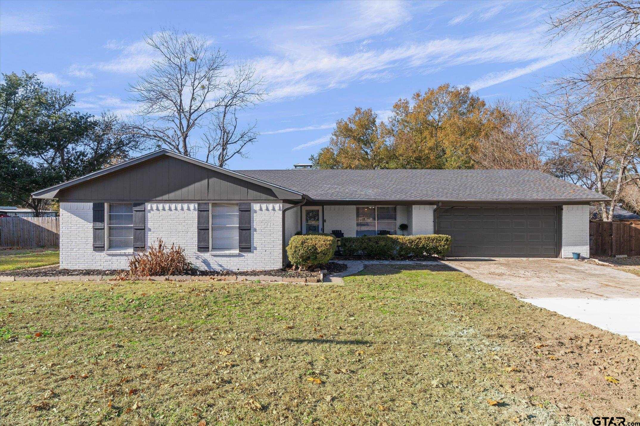 a front view of house with yard and trees in the background