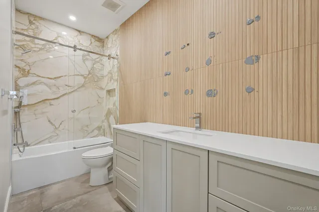 a bathroom with a granite countertop sink a toilet and shower