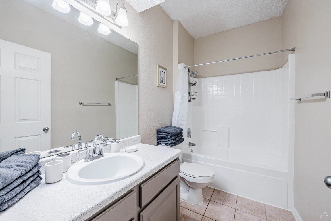 11908 Anderson Mill Road, Unit 732 Austin, TX 78726 - Photo 17 of 23 a bathroom with a granite countertop sink toilet a mirror and shower