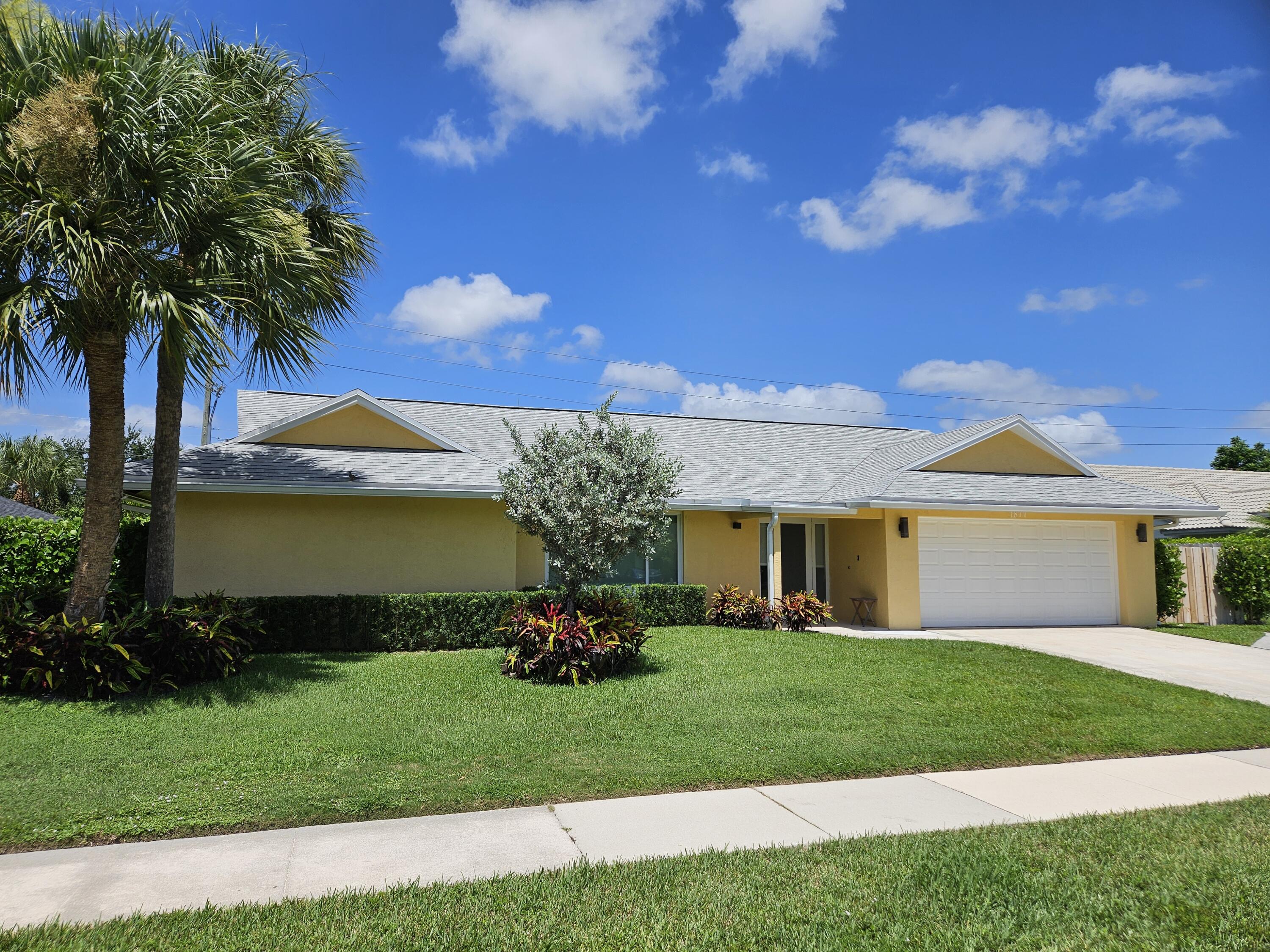 a front view of a house with a garden and trees