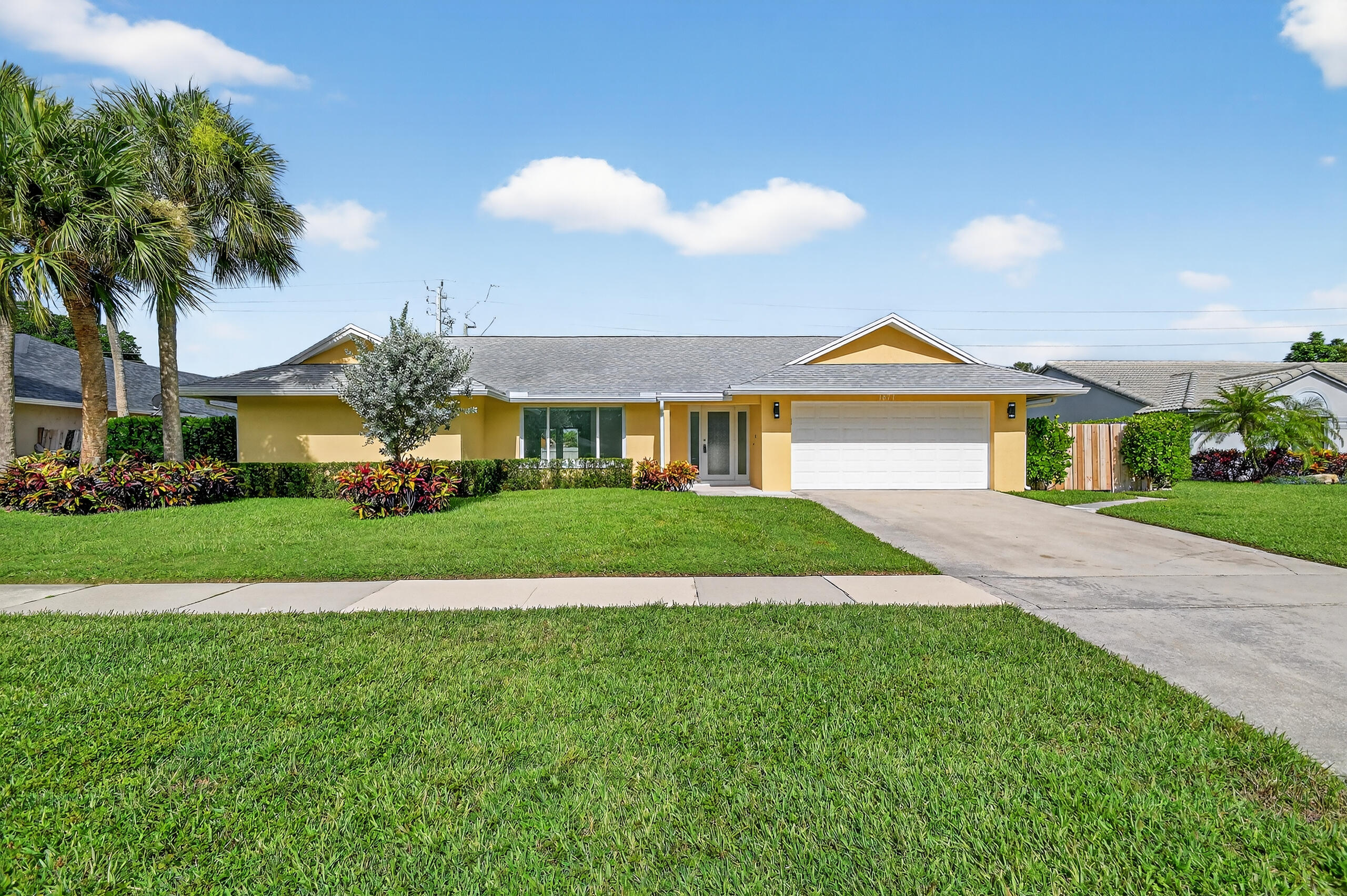 1877 Shower Tree Way Wellington, FL 33414 - Photo 3 of 53 a front view of a house with a yard and garage