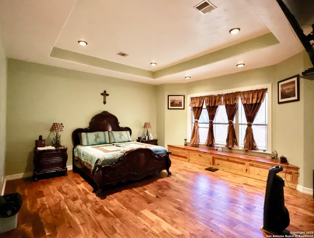 a spacious bedroom with a bed and wooden floor