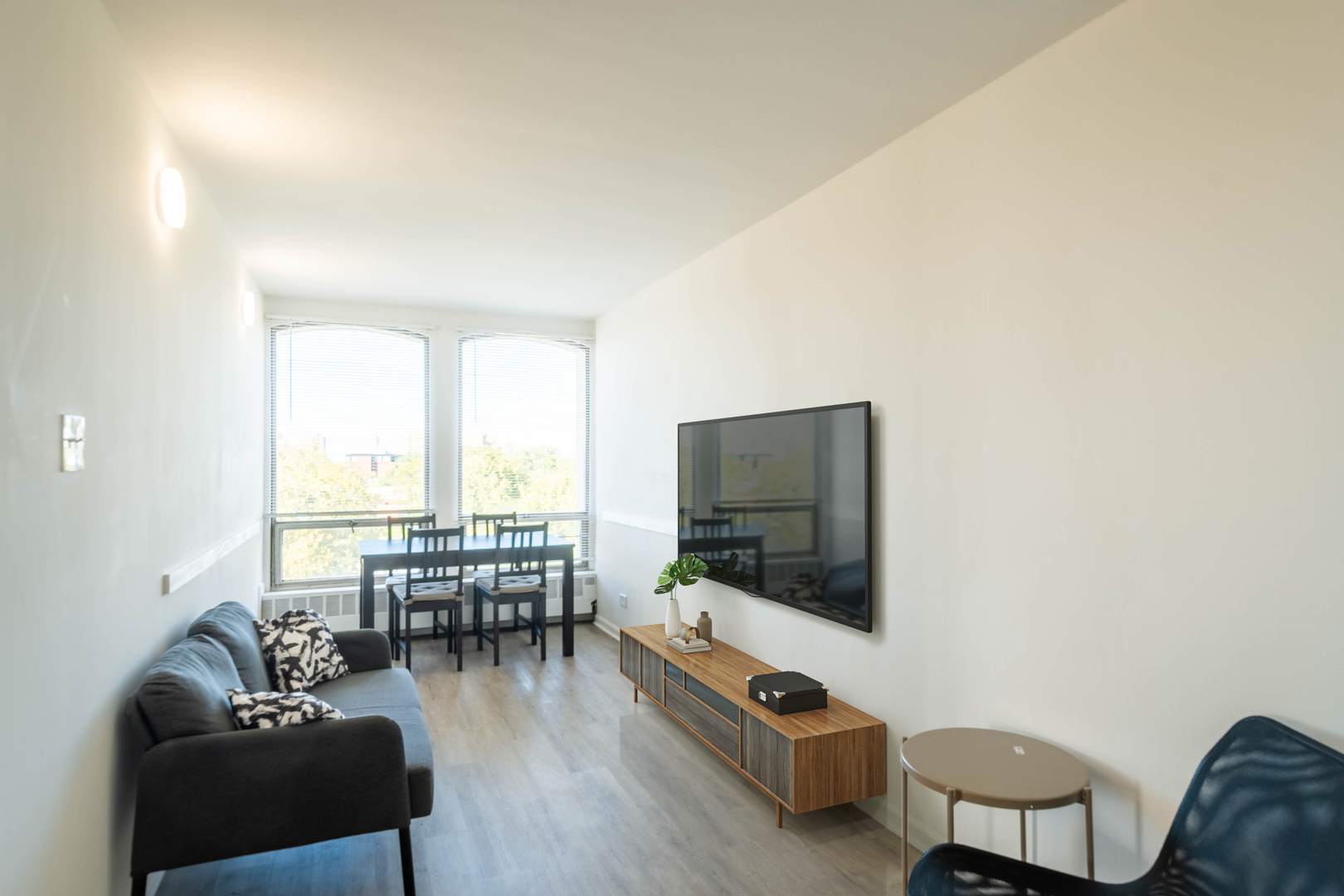1401 East 55th Street, Unit 701N Chicago, IL 60615 - Photo 2 of 10 a living room with furniture a flat screen tv and a floor to ceiling window