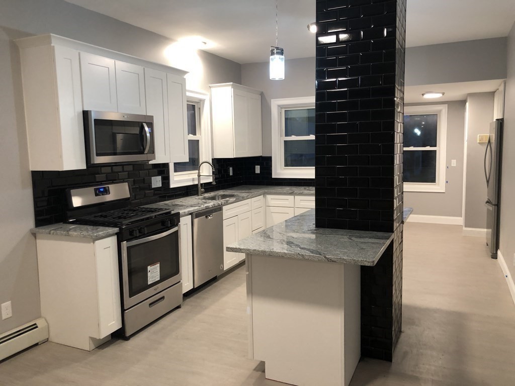 135 Winthrop Street Fall River, MA 02721 - Photo 14 of 26 a kitchen with stainless steel appliances granite countertop a stove a sink and a microwave