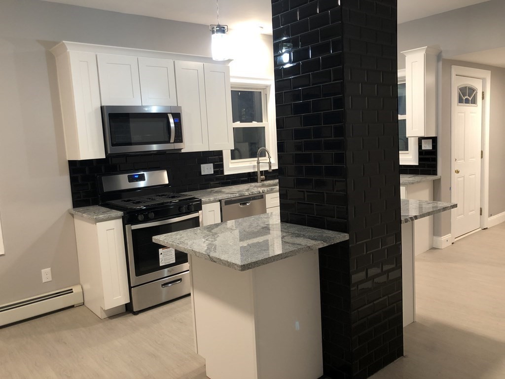 135 Winthrop Street Fall River, MA 02721 - Photo 10 of 26 a kitchen with kitchen island granite countertop a sink and a stove