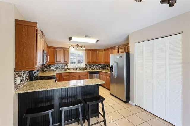 a kitchen with stainless steel appliances granite countertop a refrigerator a sink and white cabinets