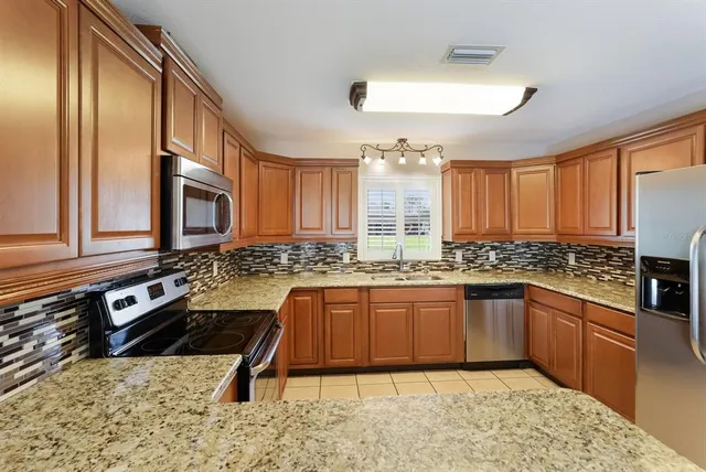 a large kitchen with granite countertop a sink and a stove