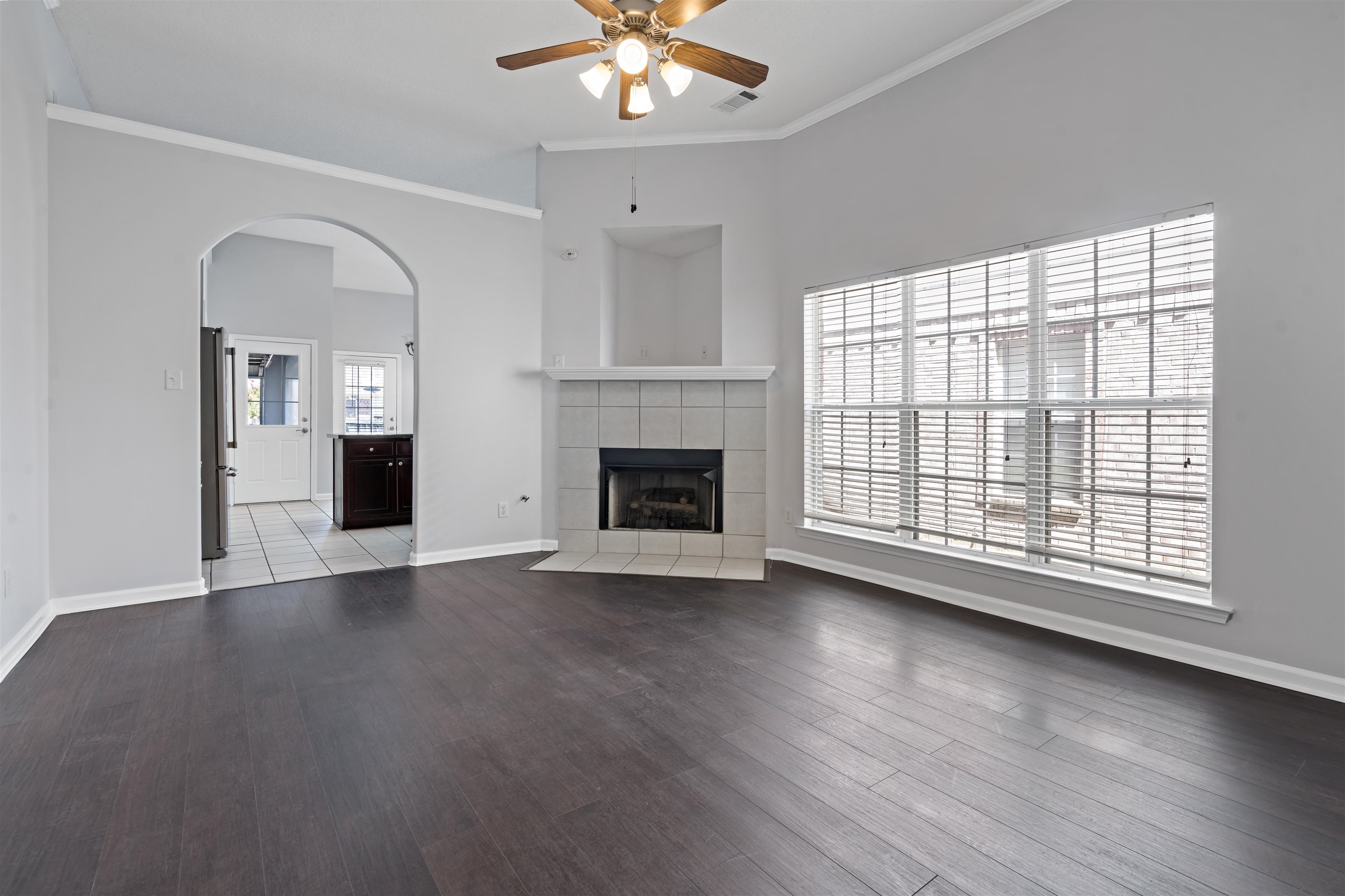 6814 Manslick Road Cordova, TN 38018 - Photo 3 of 20 Unfurnished living room with ceiling fan, a tiled fireplace, ornamental molding, and hardwood / wood-style flooring