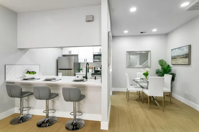 a kitchen with stainless steel appliances kitchen island granite countertop a dining table chairs and granite counter tops