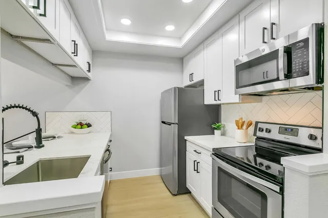 a kitchen with stainless steel appliances a stove a sink and a microwave