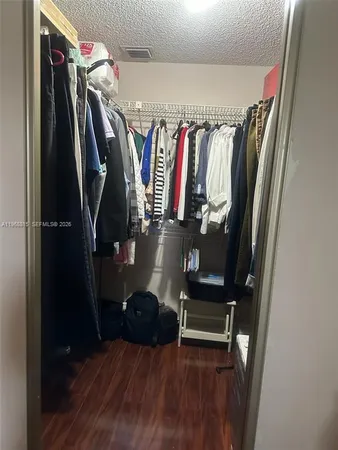 a view of walk in closet with clothes and shoes