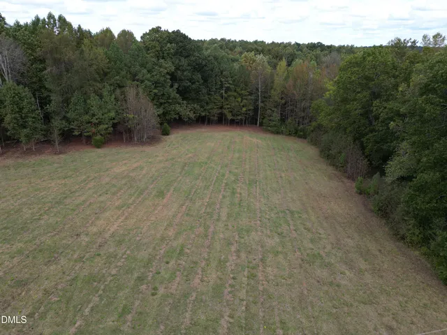 a view of a dry yard with trees in the background