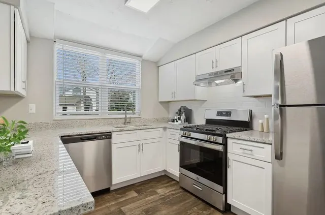 a kitchen with stainless steel appliances white cabinets and a sink