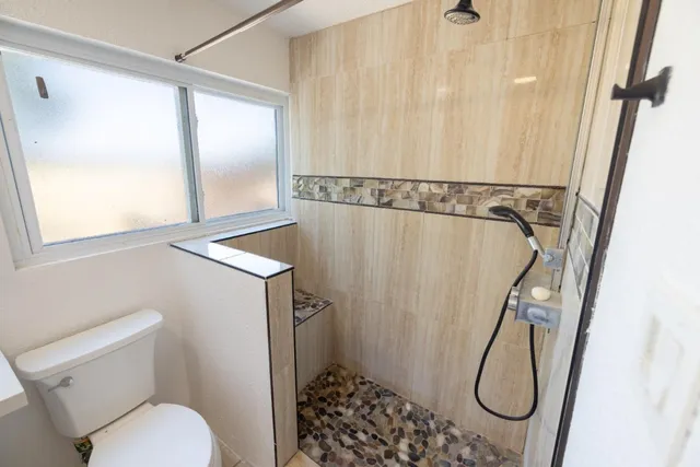 a bathroom with a granite countertop shower and a toilet
