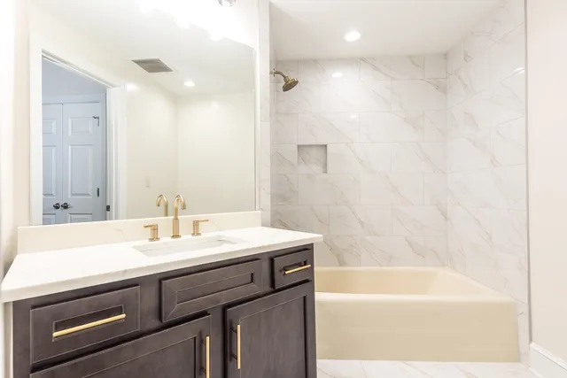 a bathroom with a sink a bathtub a mirror a vanity and a shower