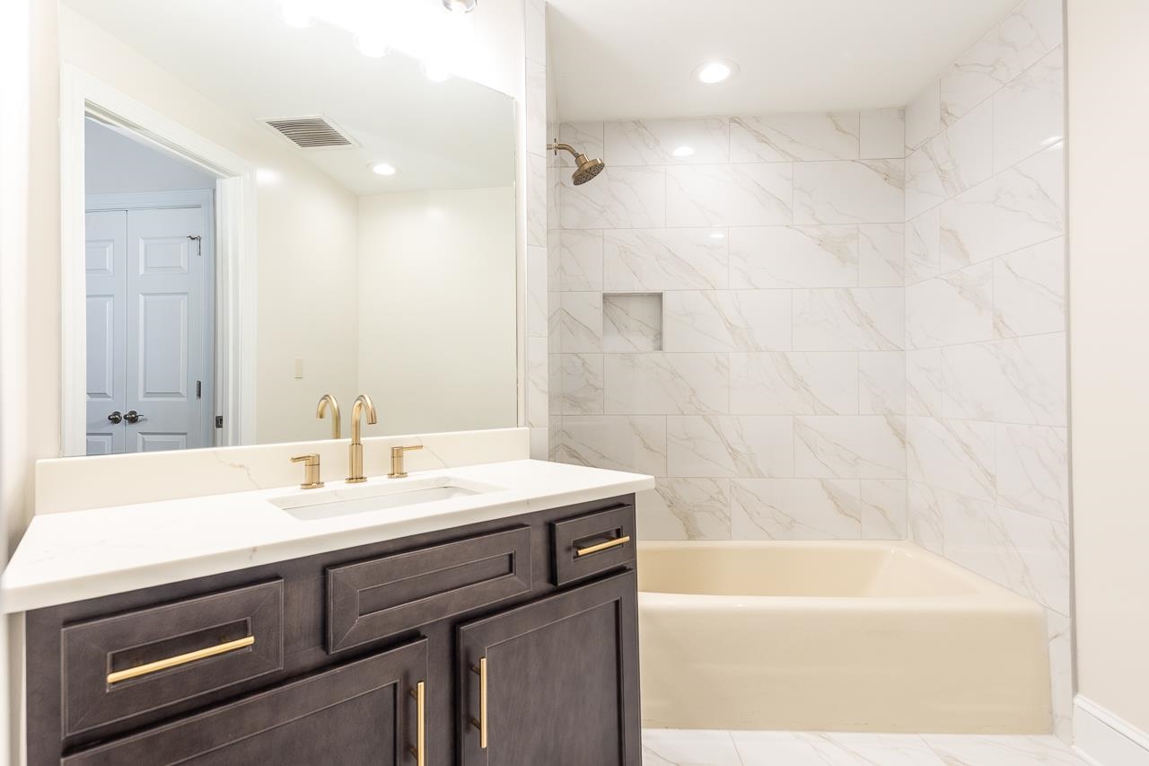 95 South Main Street, Unit 101 Memphis, TN 38103 - Photo 18 of 26 a bathroom with a sink a bathtub a mirror a vanity and a shower