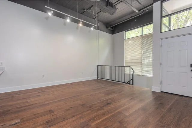 an empty room with wooden floor and windows