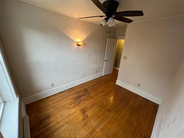 en empty room with wooden floor and fan