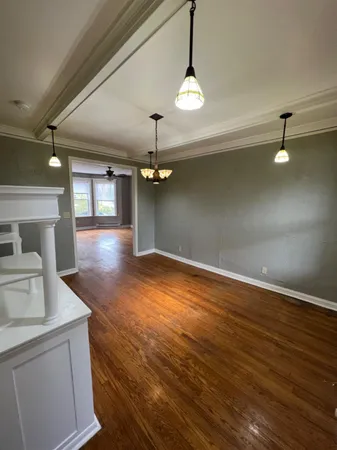 an empty room with wooden floor and chandelier