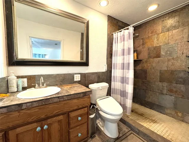 a bathroom with a granite countertop toilet sink and mirror