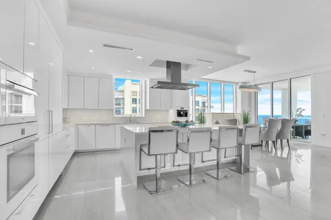 a kitchen with stainless steel appliances kitchen island granite countertop a table chairs sink and cabinets