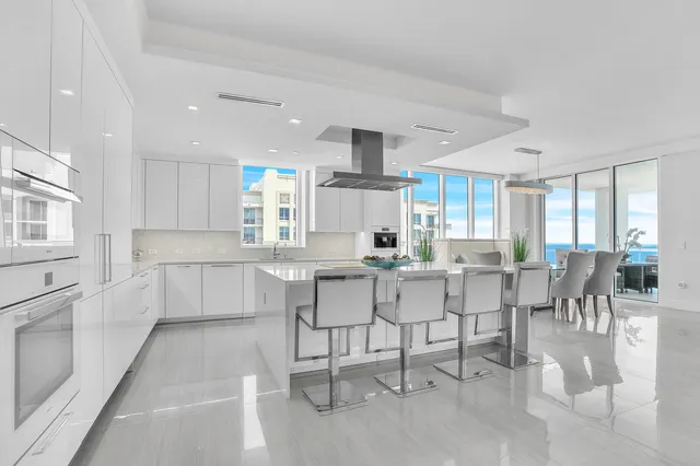 a kitchen with stainless steel appliances kitchen island granite countertop a table chairs sink and cabinets