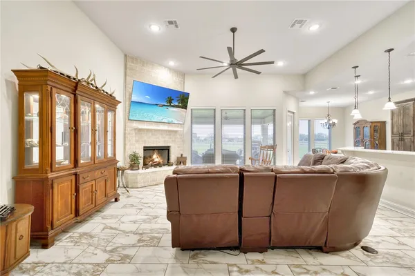 a living room with couches a fireplace and kitchen view with wooden floor