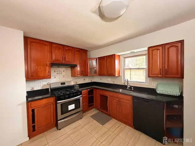 a kitchen with granite countertop a sink a stove and cabinets